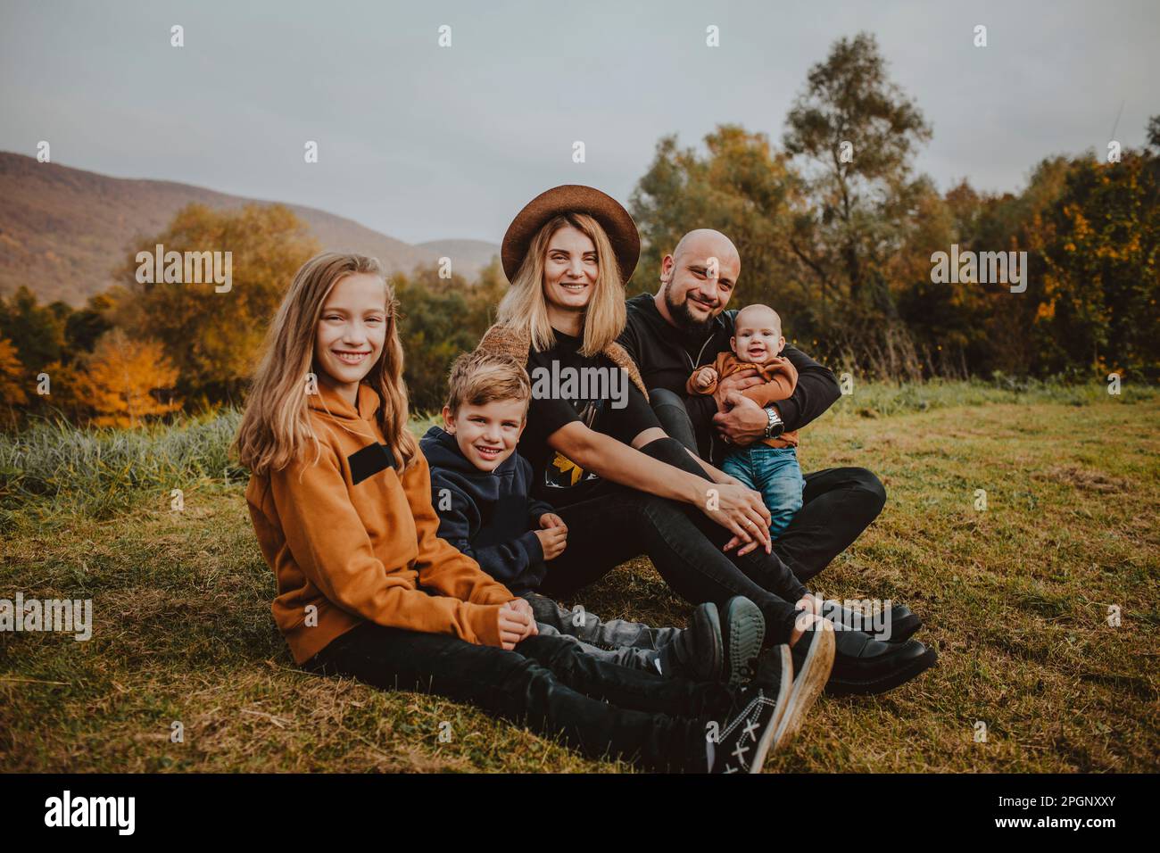 Happy family sitting on grass at park Stock Photo - Alamy