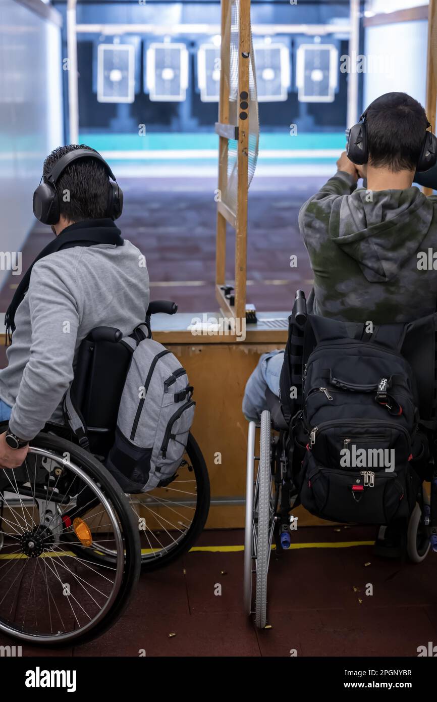 Two Men in Wheelchair Shooting with a Gun on Shooting Range with Target