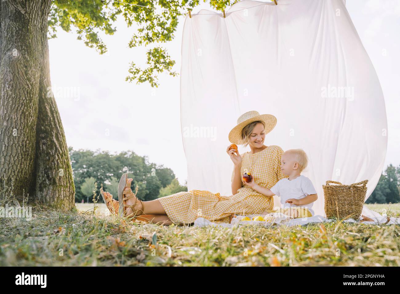 Happy mother and son with apples sitting in park Stock Photo