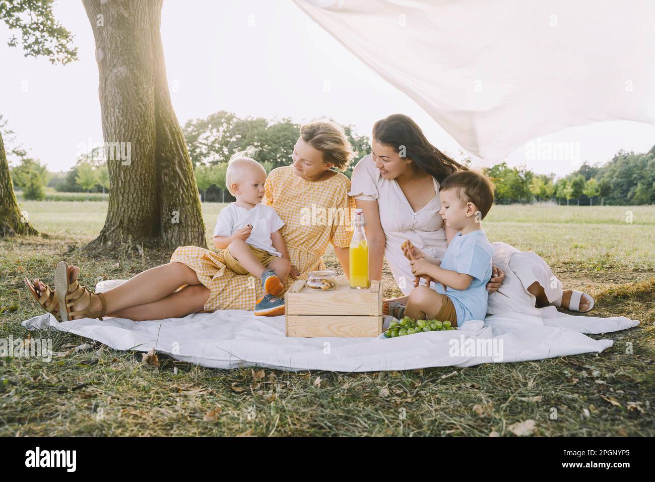 Women spending time with sons in park Stock Photo