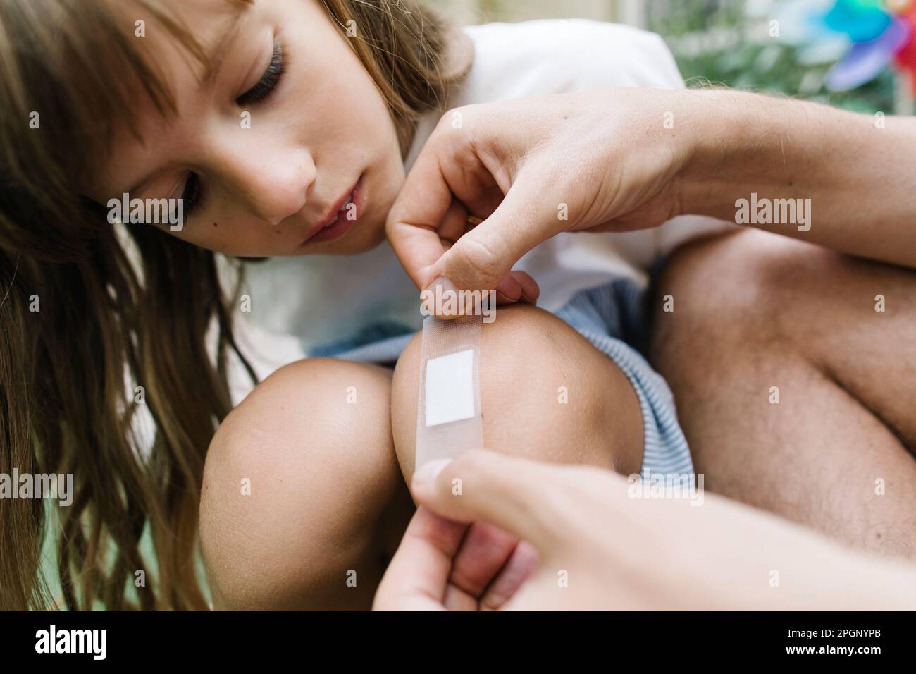 Father applying bandage on daughters knee Stock Photo