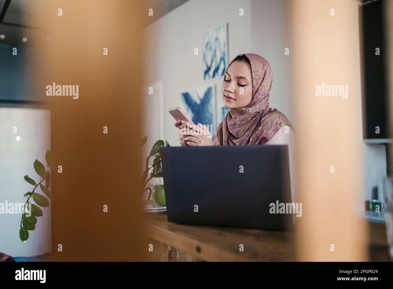 Freelancer text messaging through smart phone at home office Stock Photo