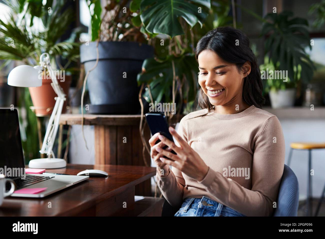Happy freelancer text messaging through smart phone at loft office Stock Photo