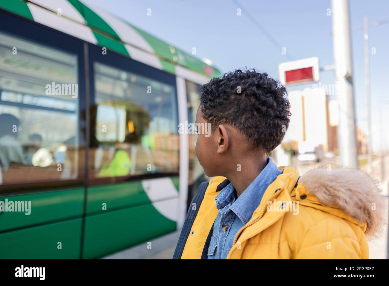 Boy wearing parka coat looking at tram Stock Photo