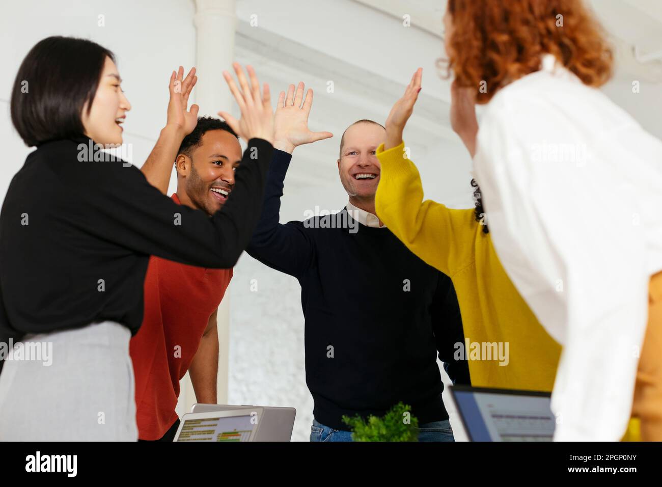 Happy multiracial colleagues giving high-five in office Stock Photo - Alamy