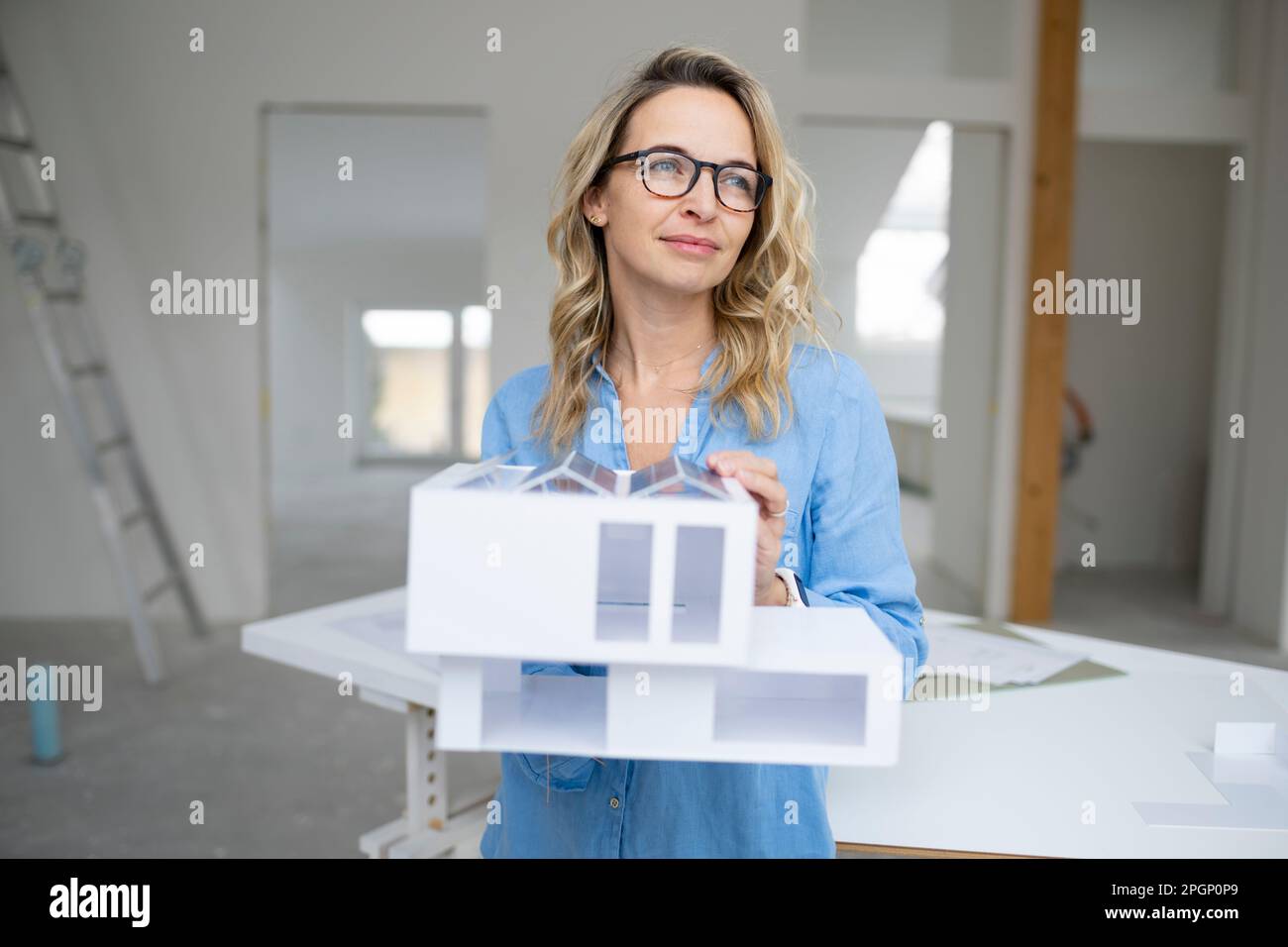 Architect holding model home standing at site Stock Photo