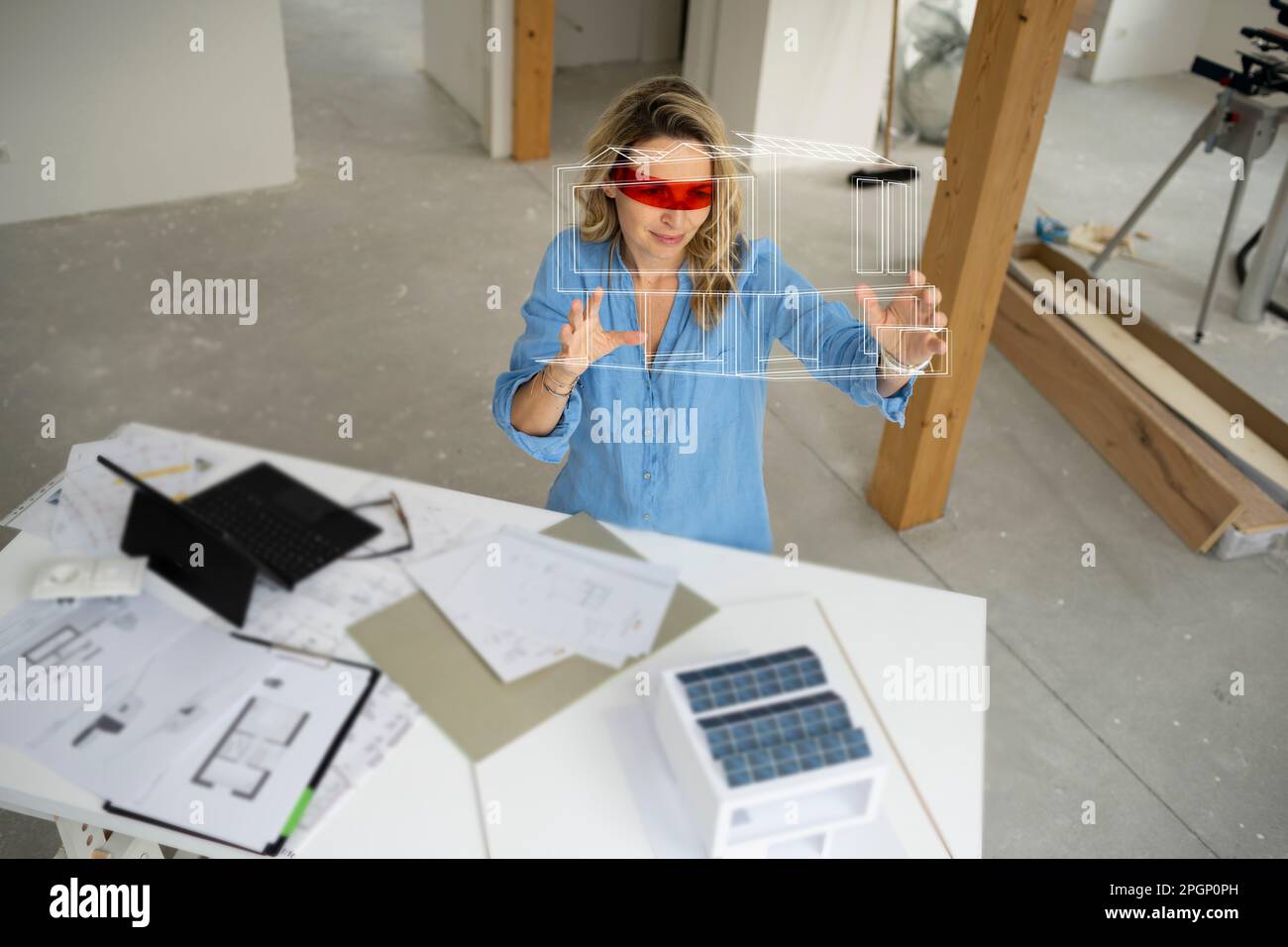 Architect wearing virtual reality simulator gesturing and examining house model Stock Photo