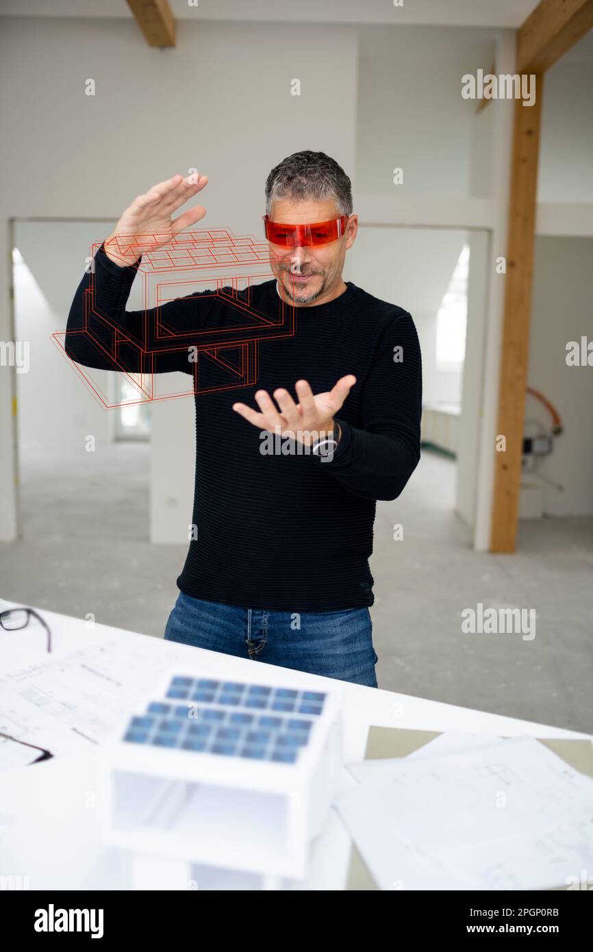 Architect wearing virtual reality simulator examining model home at construction site Stock Photo