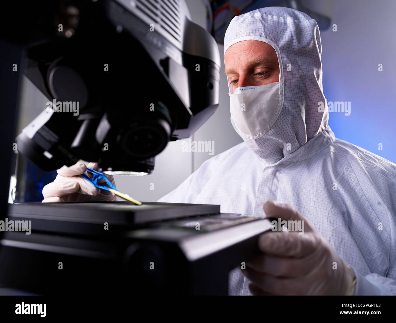 Engineer examining computer chip through microscope in laboratory Stock