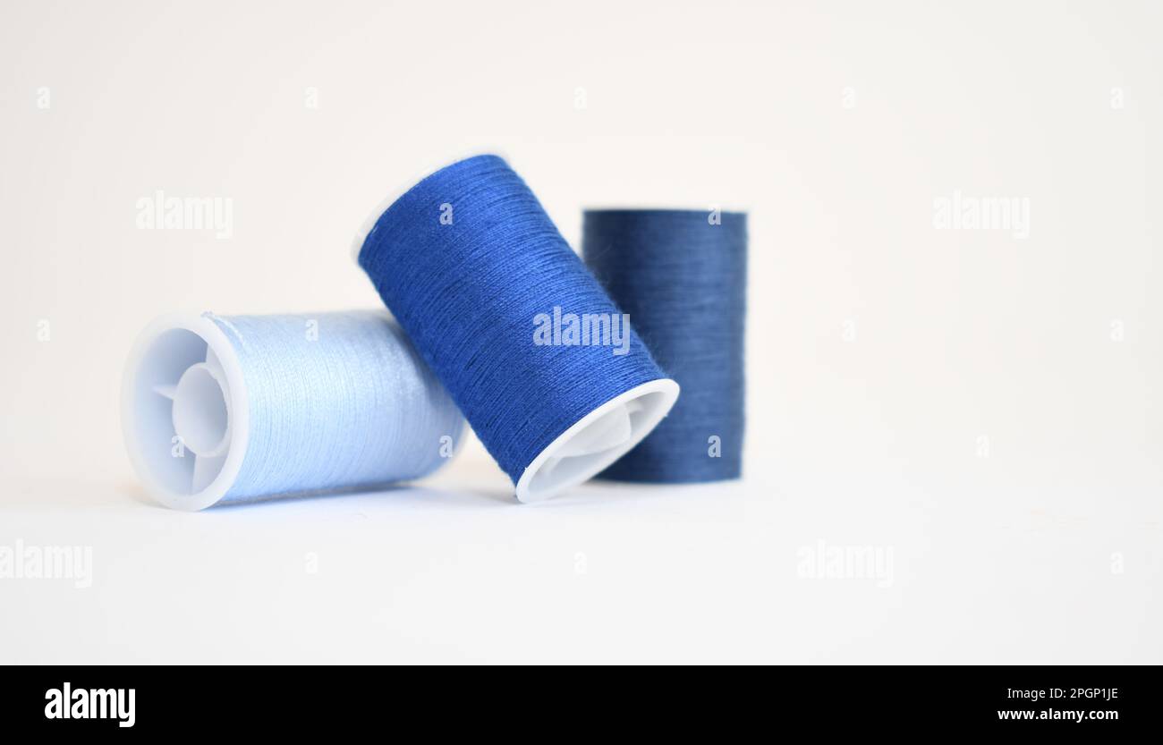 Three spools of blue yarn in different shades on a white background Stock Photo