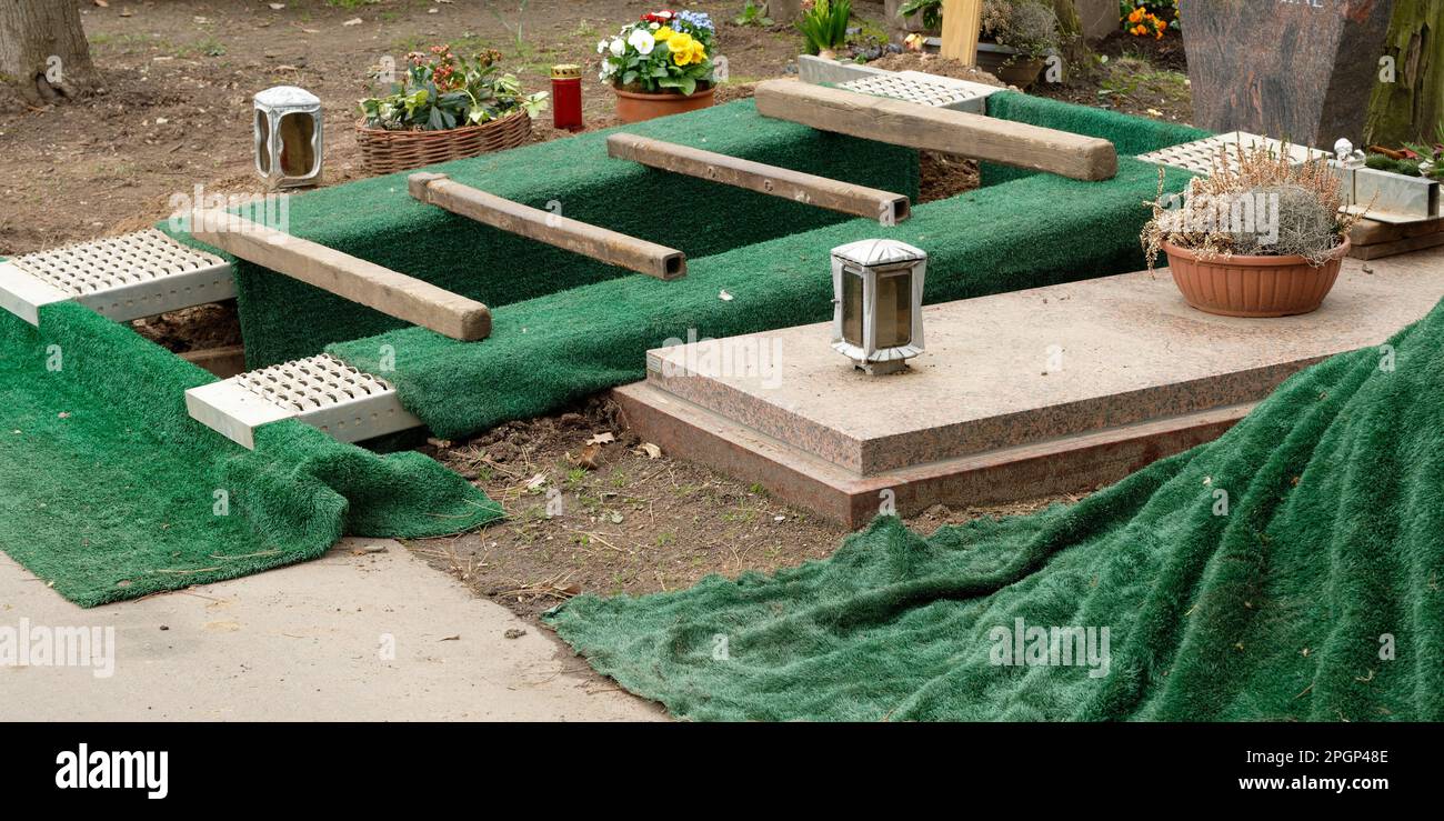 an dug grave with green grass mats just before a burial in a cemetery Stock Photo