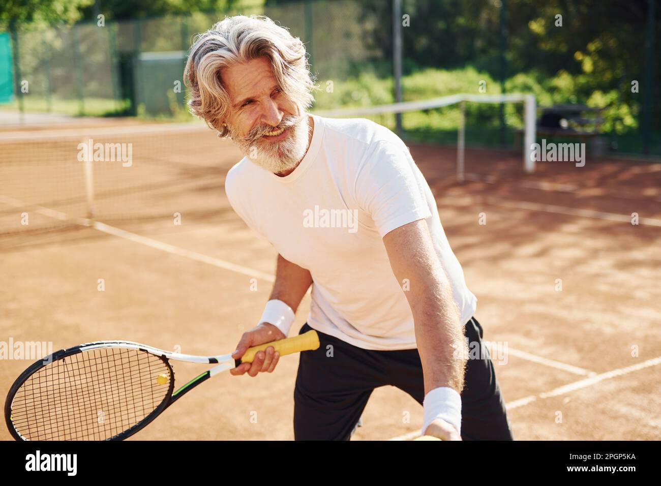 Man With Racket Playing game. Senior modern stylish man with racket outdoors on tennis ...