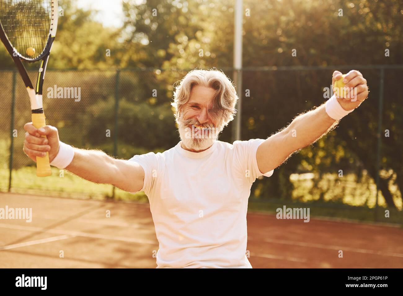 Man With Racket Celebrating victory. Senior modern stylish man with racket outdoors on ...