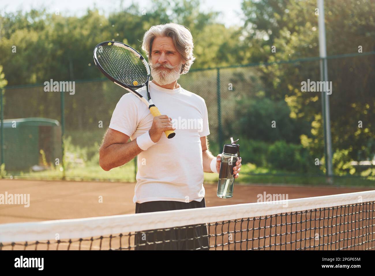 Man Using Tennis Racket Holding racket. Senior modern stylish man with racket outdoors on ...