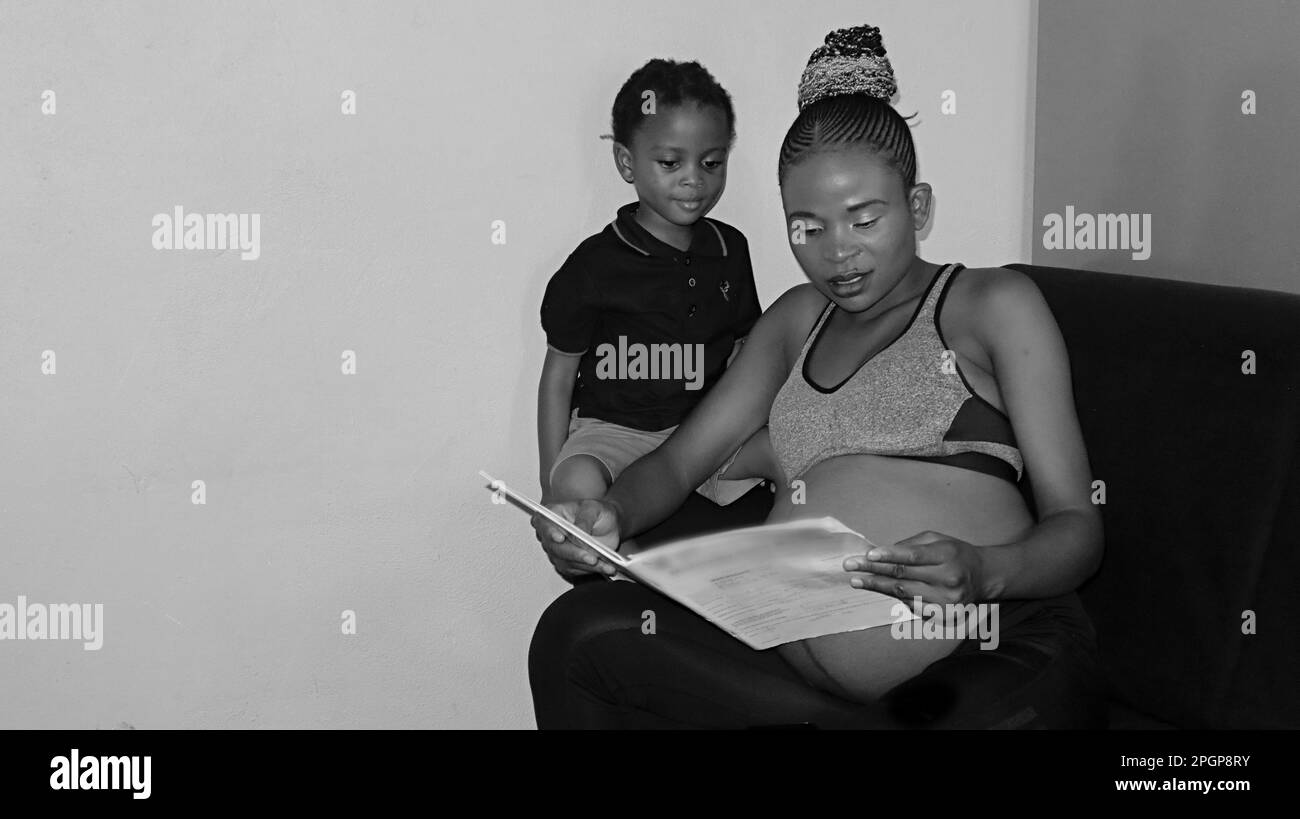black African pregnant woman home schooling her son Stock Photo