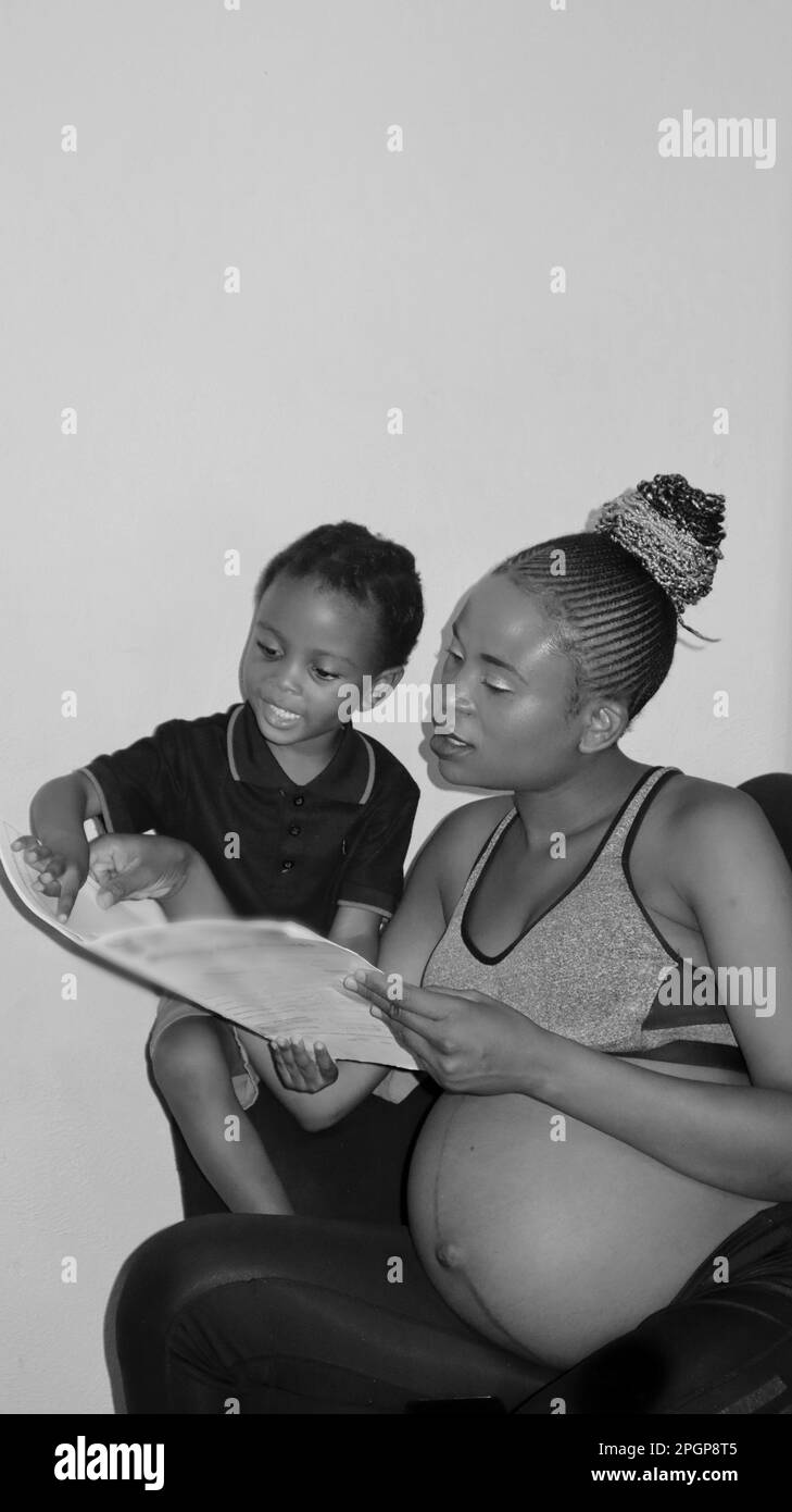 black African pregnant woman home schooling her son Stock Photo