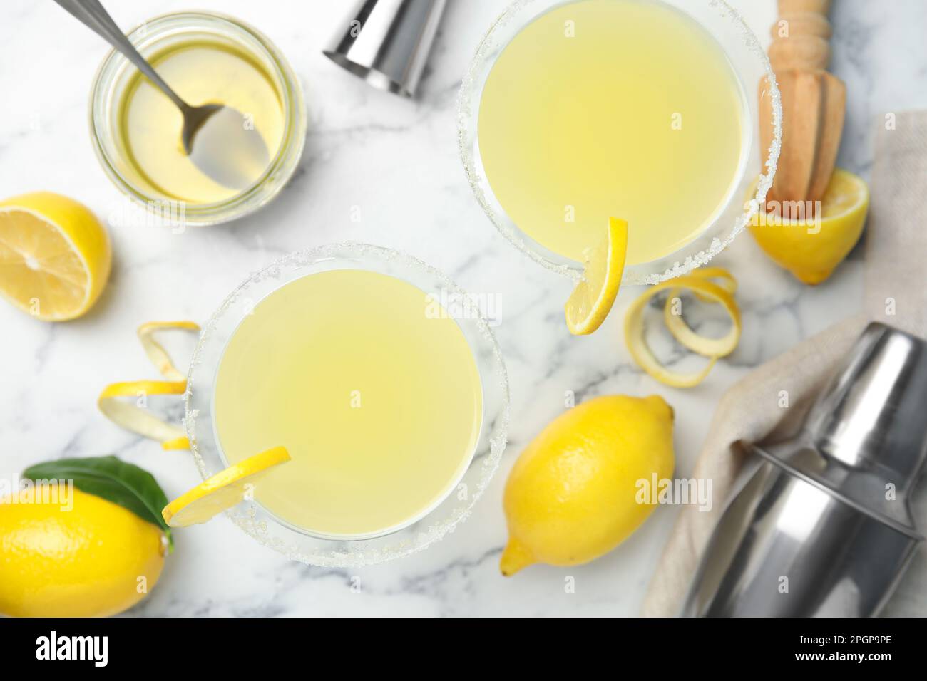 Delicious bee's knees cocktails and ingredients on white marble table