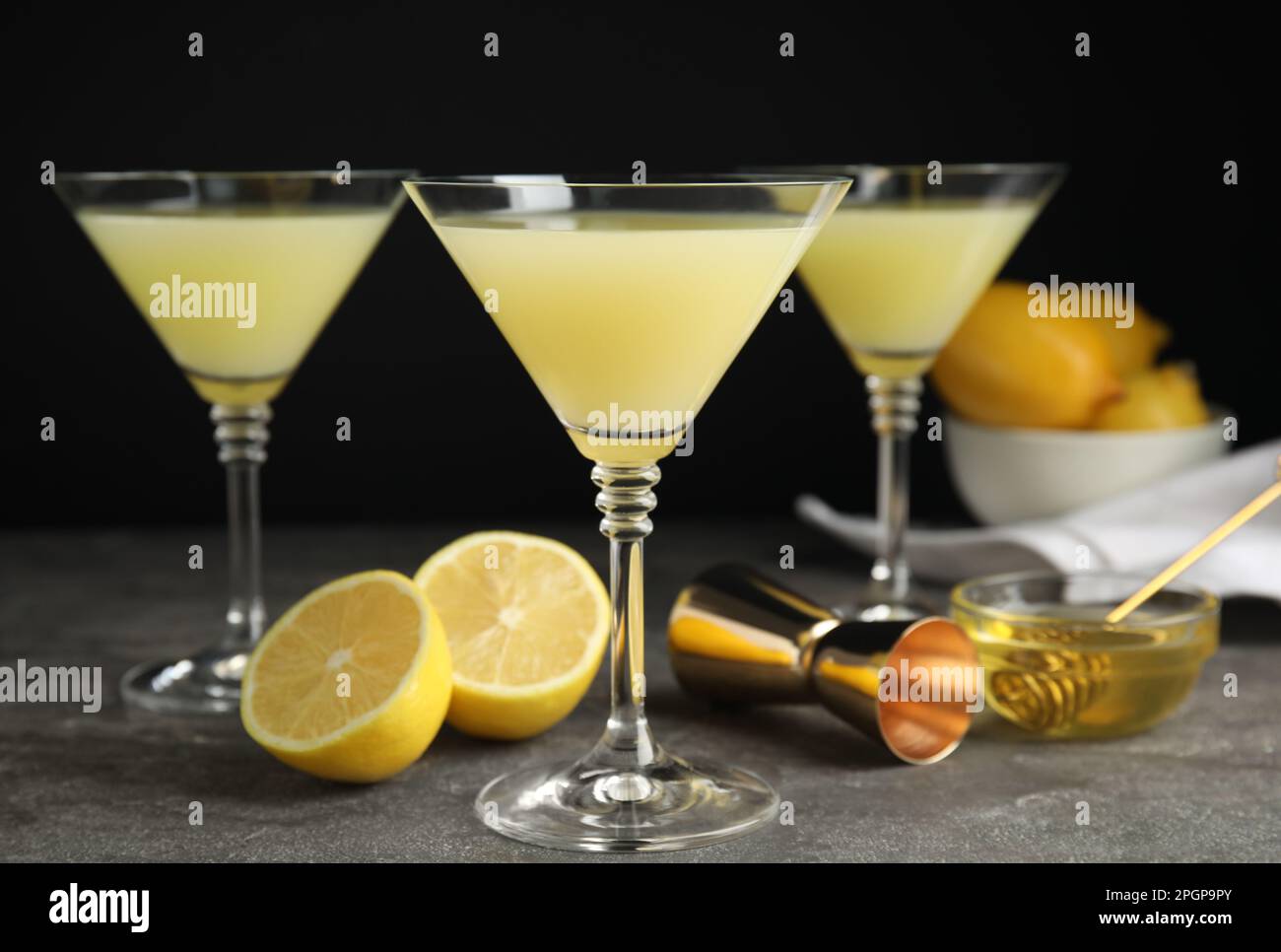 Delicious bee's knees cocktails and ingredients on grey table against