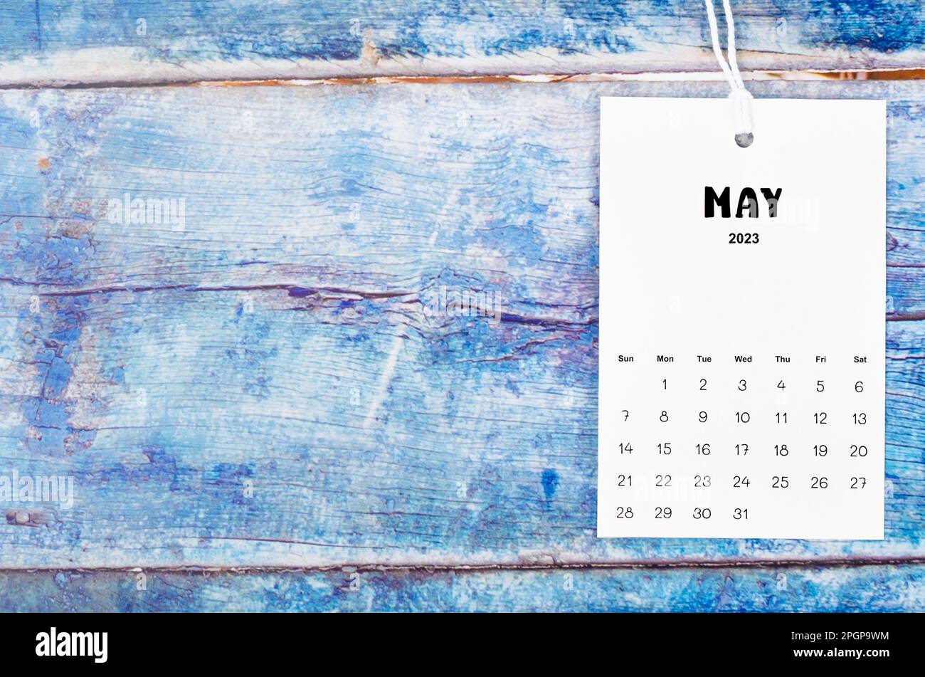 May 2023 calendar page hanged with white rope on old blue wooden