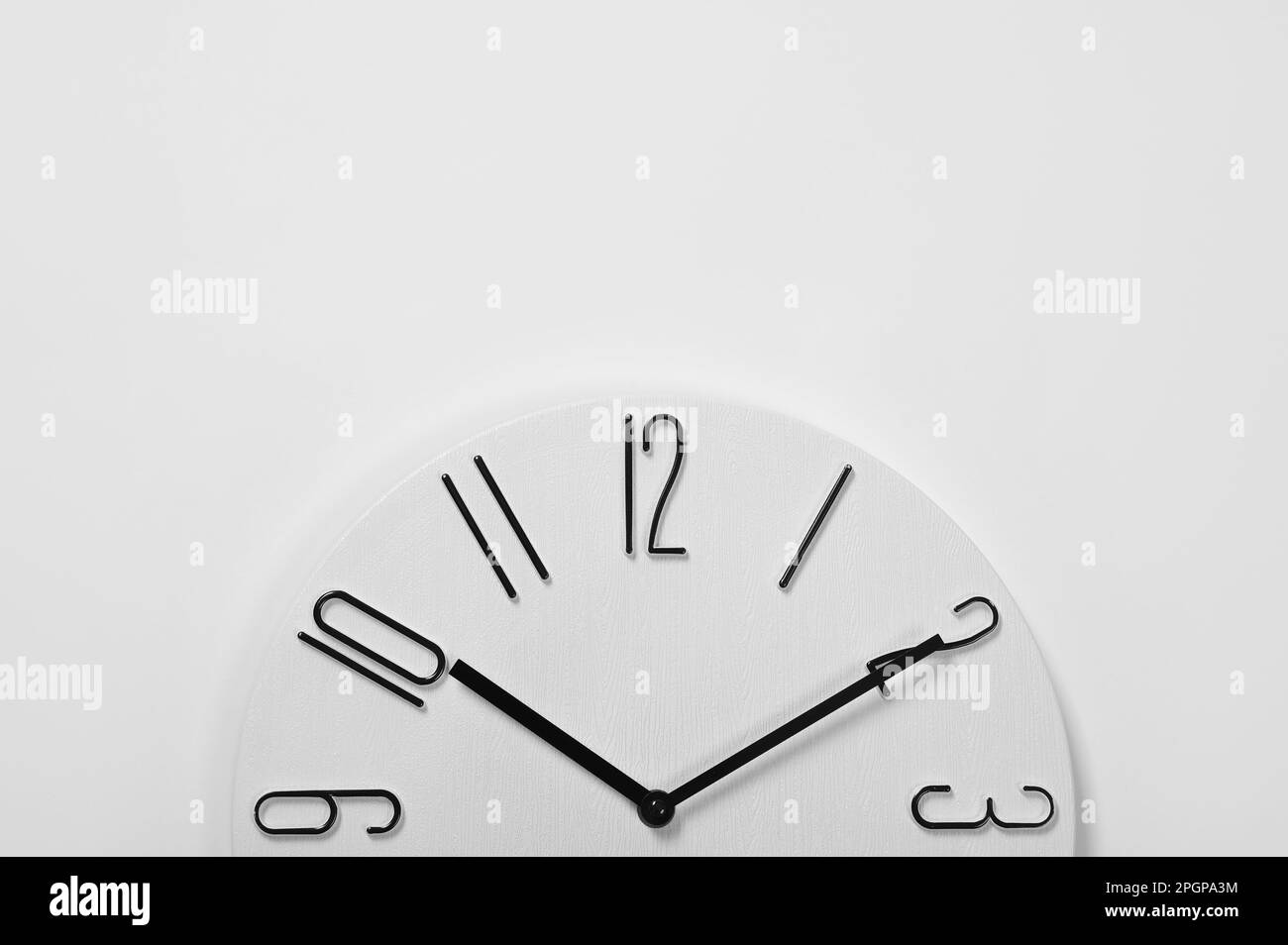 Stylish analog clock hanging on white wall, space for text Stock Photo