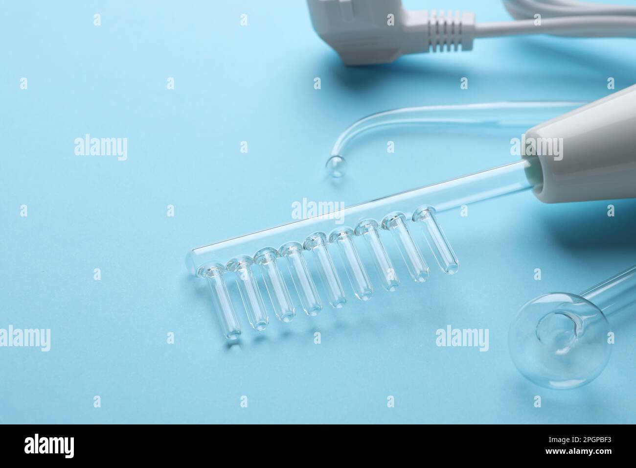 Modern darsonval with nozzles on light blue background, closeup. Space ...