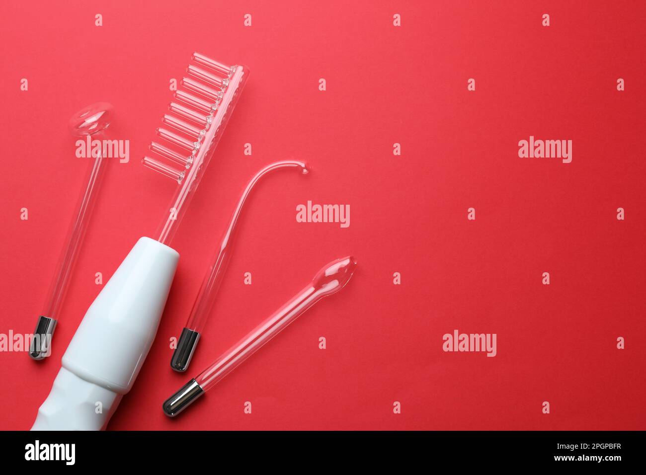 Modern darsonval with nozzles on red background, flat lay. Space for ...