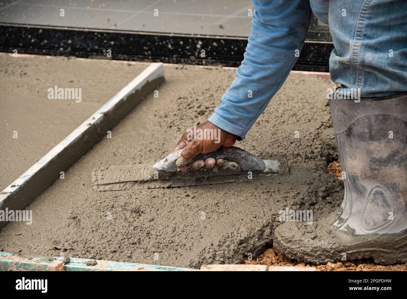 mason's hands laying cement on the floor Stock Photo Alamy