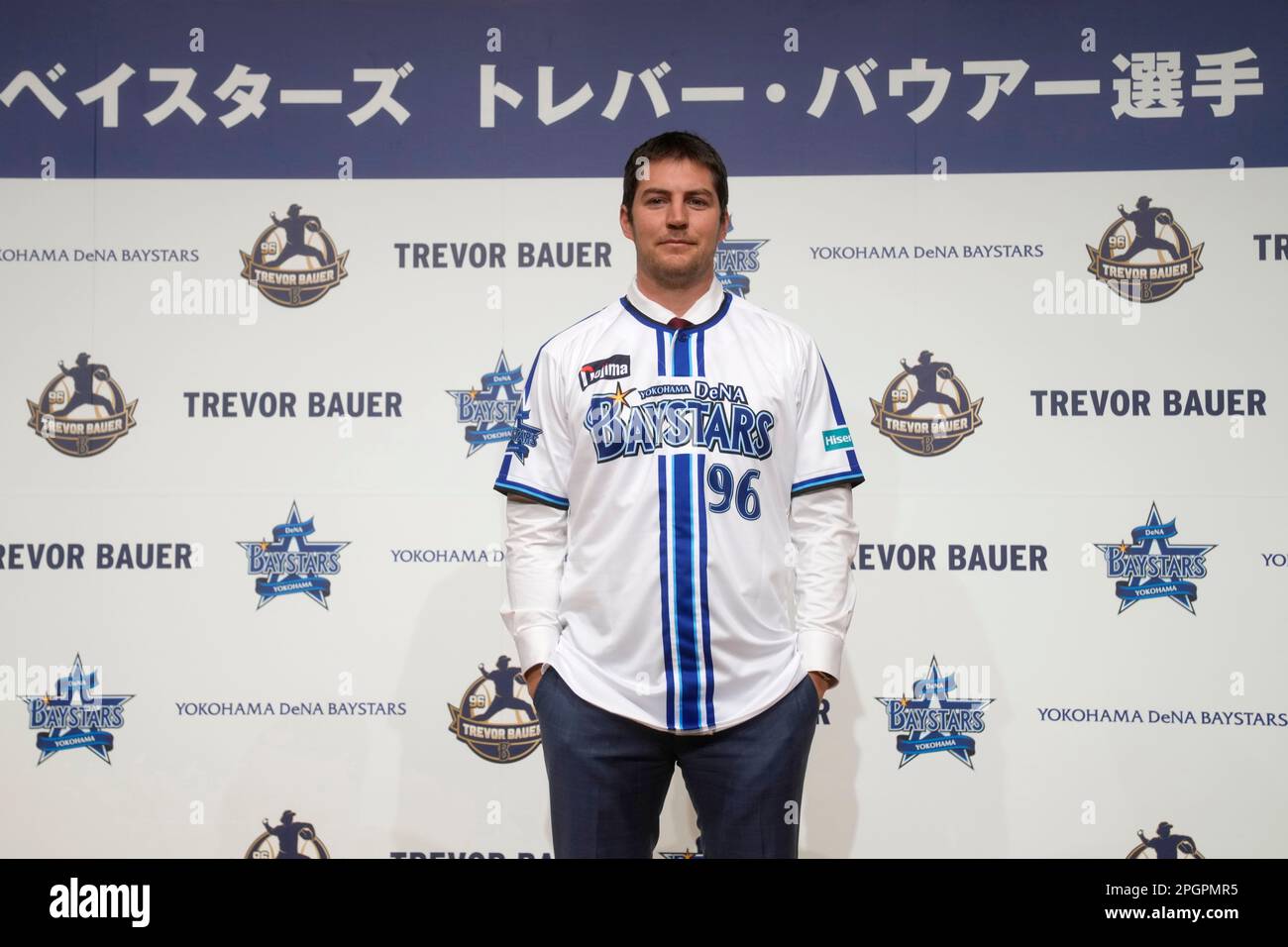 Trevor Bauer shows his new uniform and cap of Yokohama DeNA BayStars with  Tatsuhiro Hagiwara, left, senior director of Team Operations Department  during a photo session of the news conference Friday, March