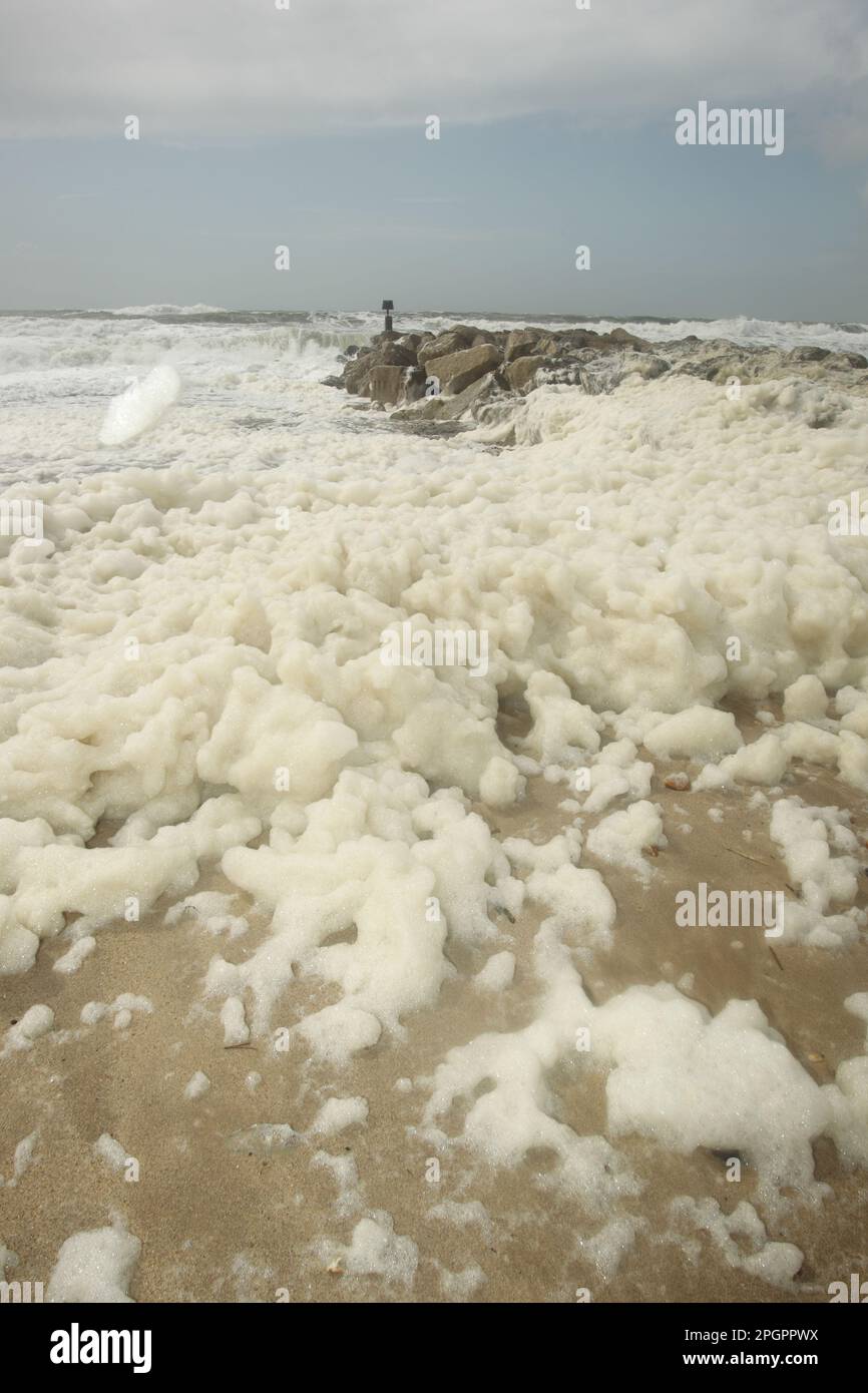 Sea foam washes up on the beach after a storm, Hengistbury Head, Dorset, England, United Kingdom Stock Photo