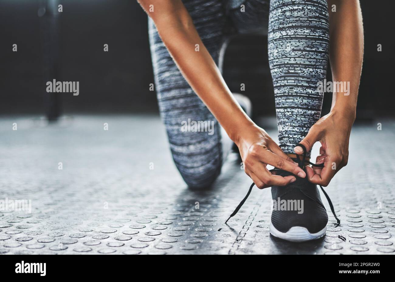 Image showcasing If the shoe fits, workout. a woman tying her shoelaces in a gym Stock ...