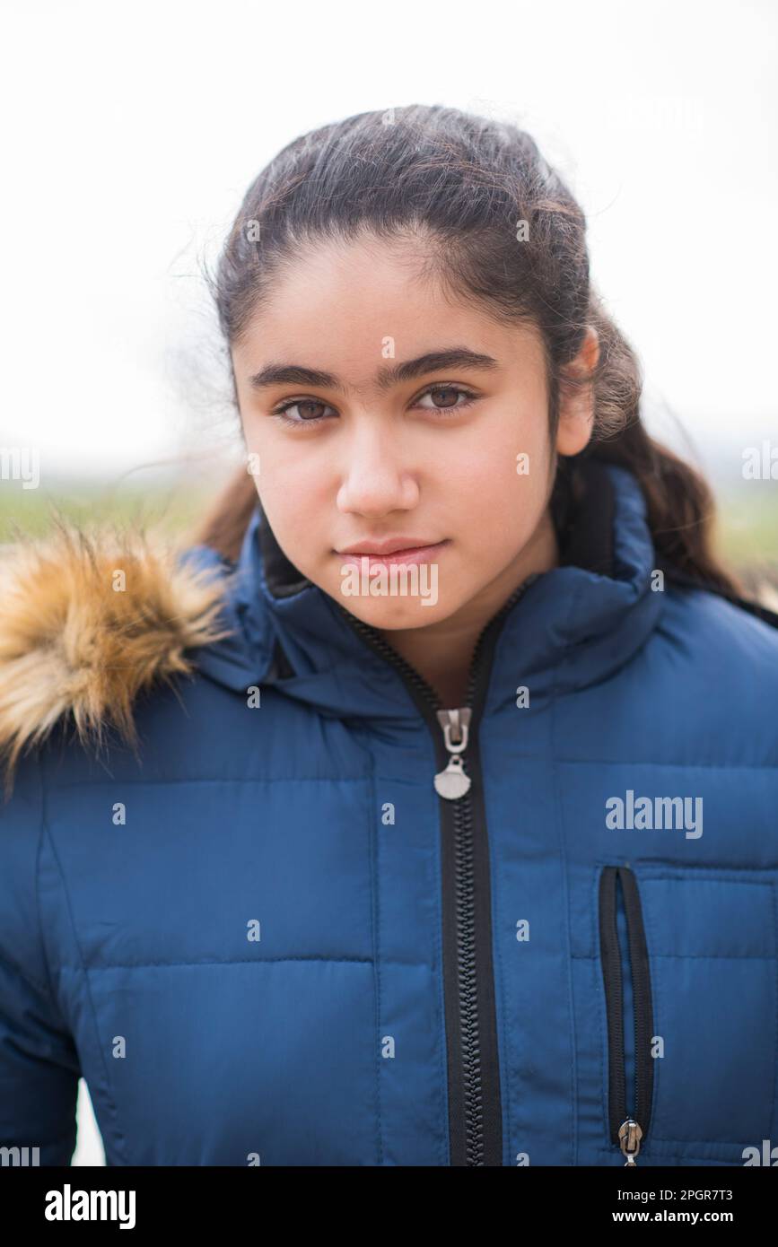 Beautiful teenage girl in winter coat looking at camera outdoors Stock Photo