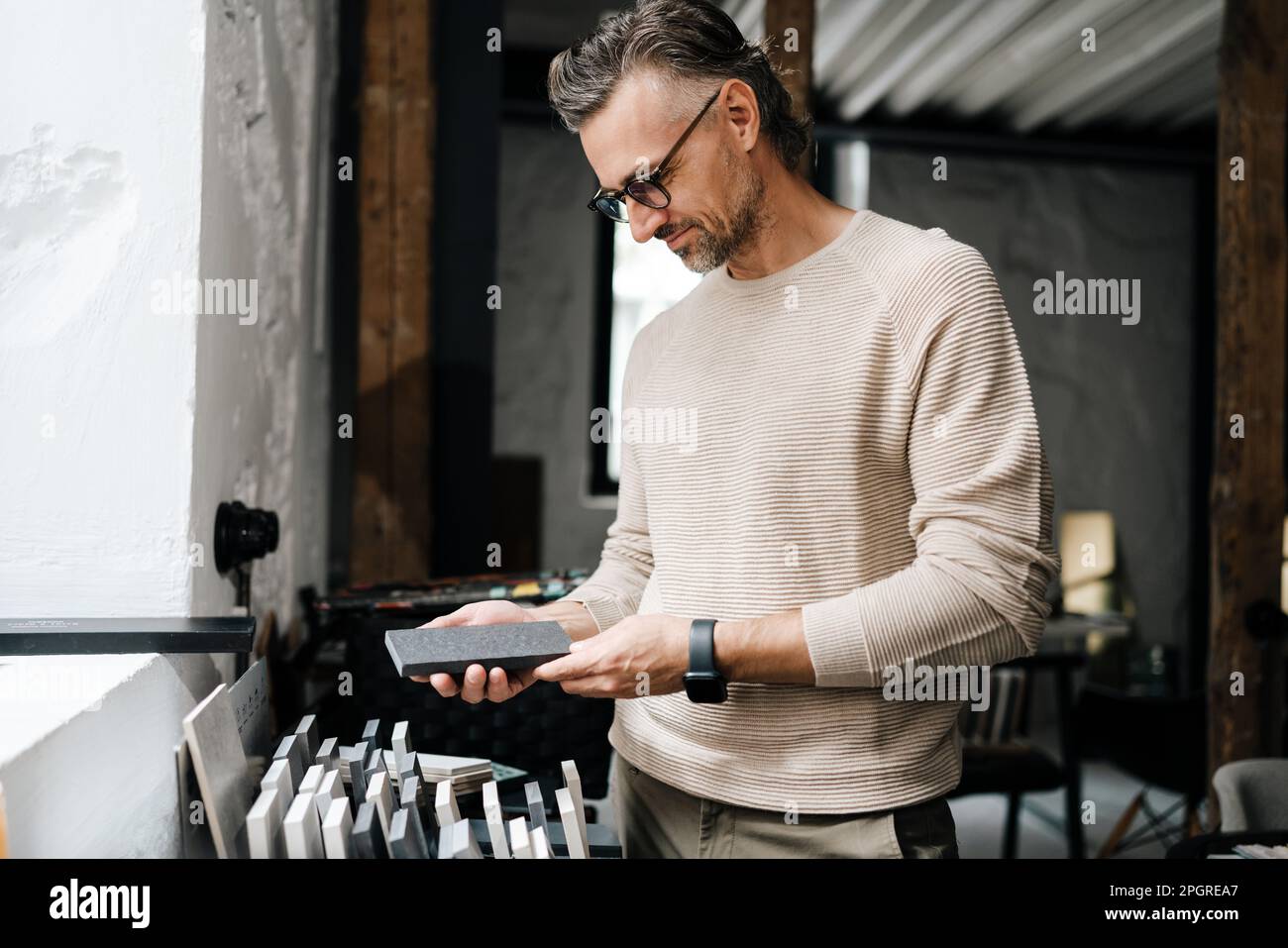 White middle-aged male interior designer in eyeglasses working with samples in workshop Stock Photo