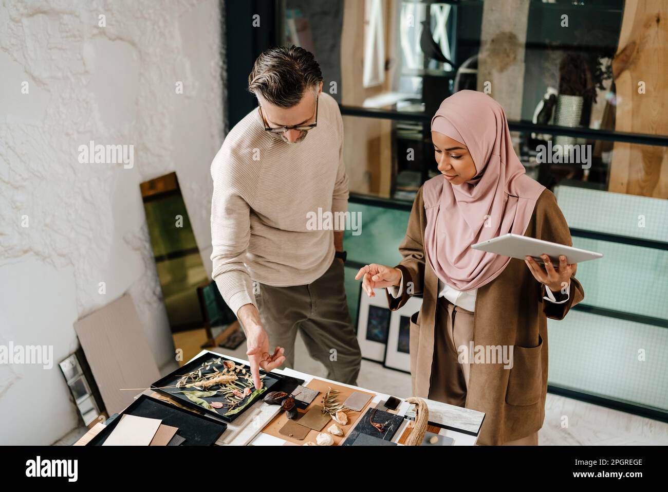 Two multiracial colleagues designers using tablet computer while working together in workshop Stock Photo