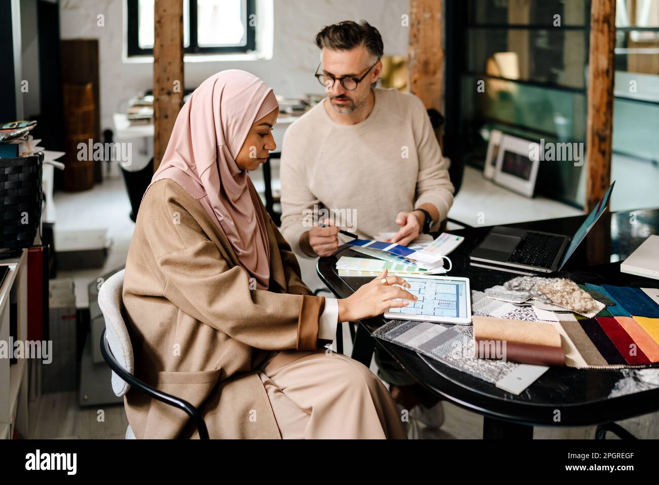 Two multinational colleagues designers working on computers together at cozy workshop Stock Photo