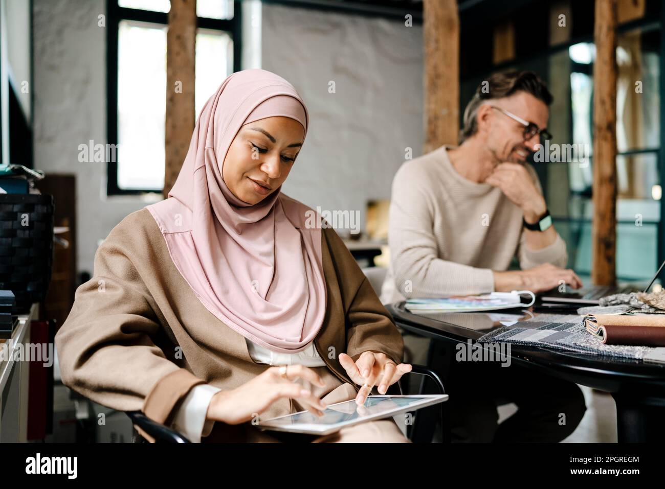 Two multinational colleagues designers working with computers together sitting at table in office Stock Photo