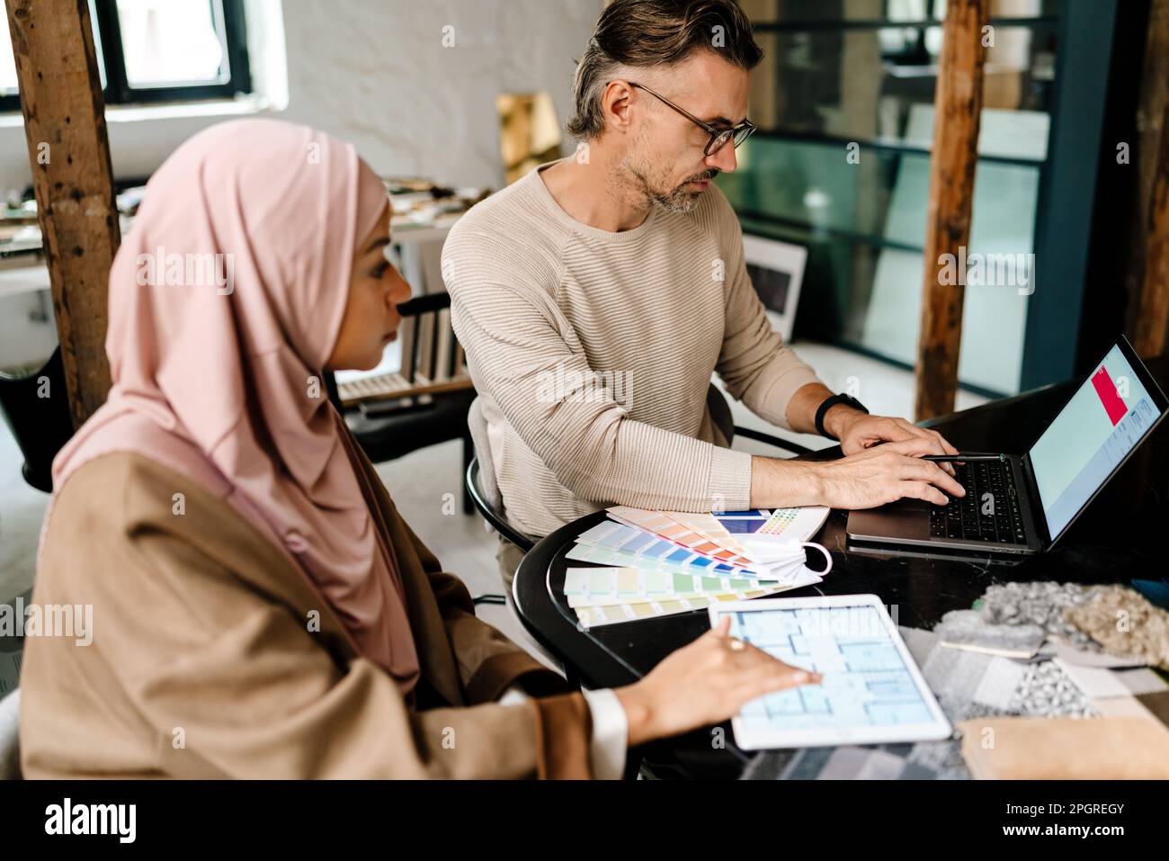 Two multinational colleagues designers working with computers together sitting at table in office Stock Photo