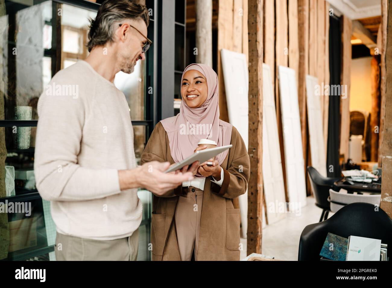Two cheerful multiracial colleagues designers using tablet while working together in modern office Stock Photo