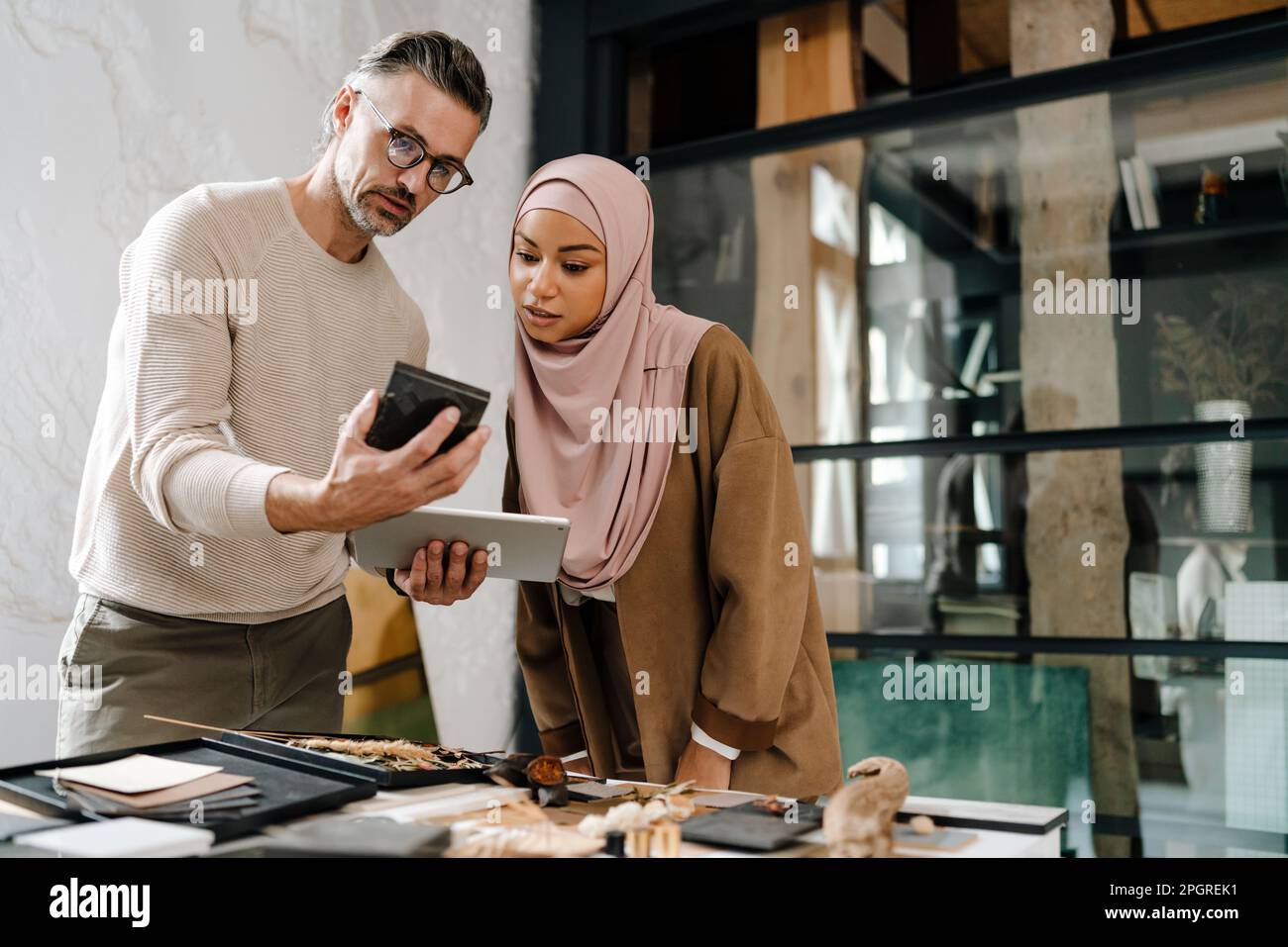 Two multiracial colleagues designers using tablet while working together in modern office Stock Photo