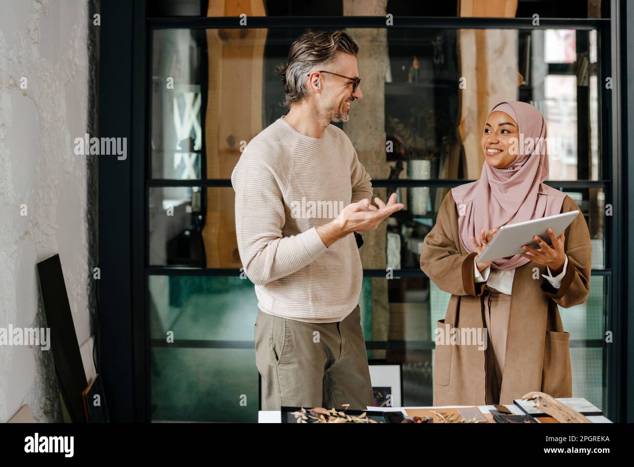 Two multiracial colleagues designers using tablet while working together in modern office Stock Photo