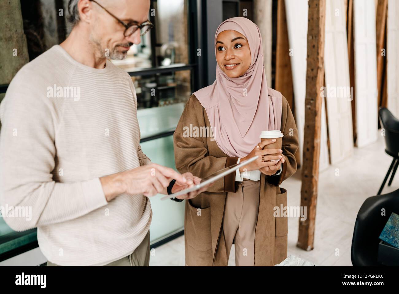 Two multiracial colleagues designers using tablet computer while working together in modern office Stock Photo