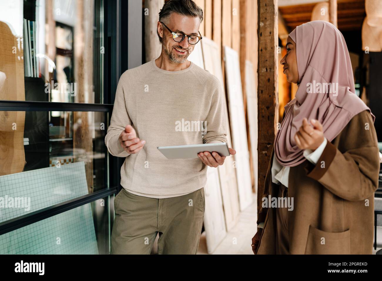 Two cheerful multiracial colleagues using tablet while working together in modern office Stock Photo