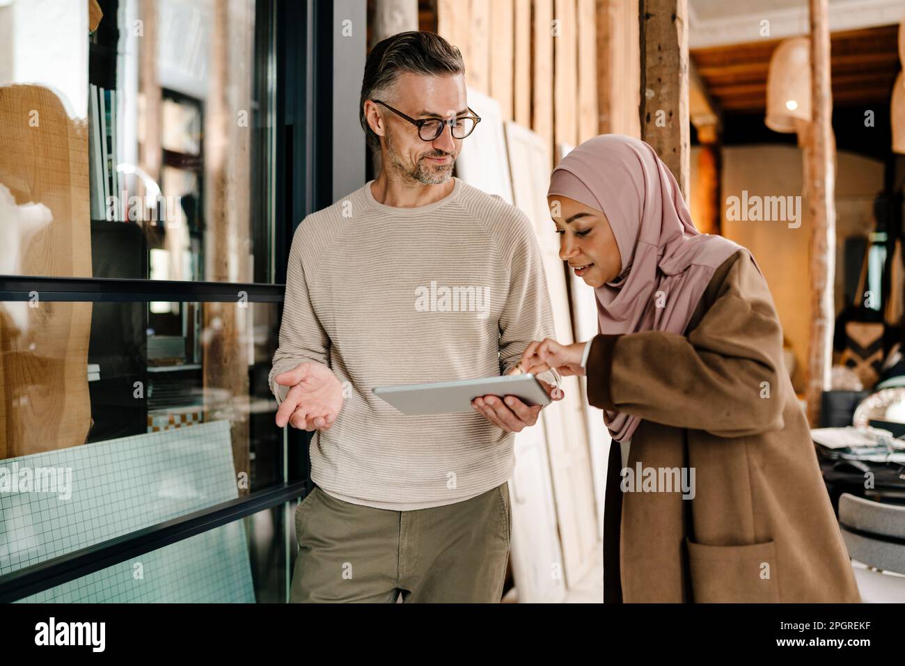 Two cheerful multiracial colleagues using tablet while working together in modern office Stock Photo