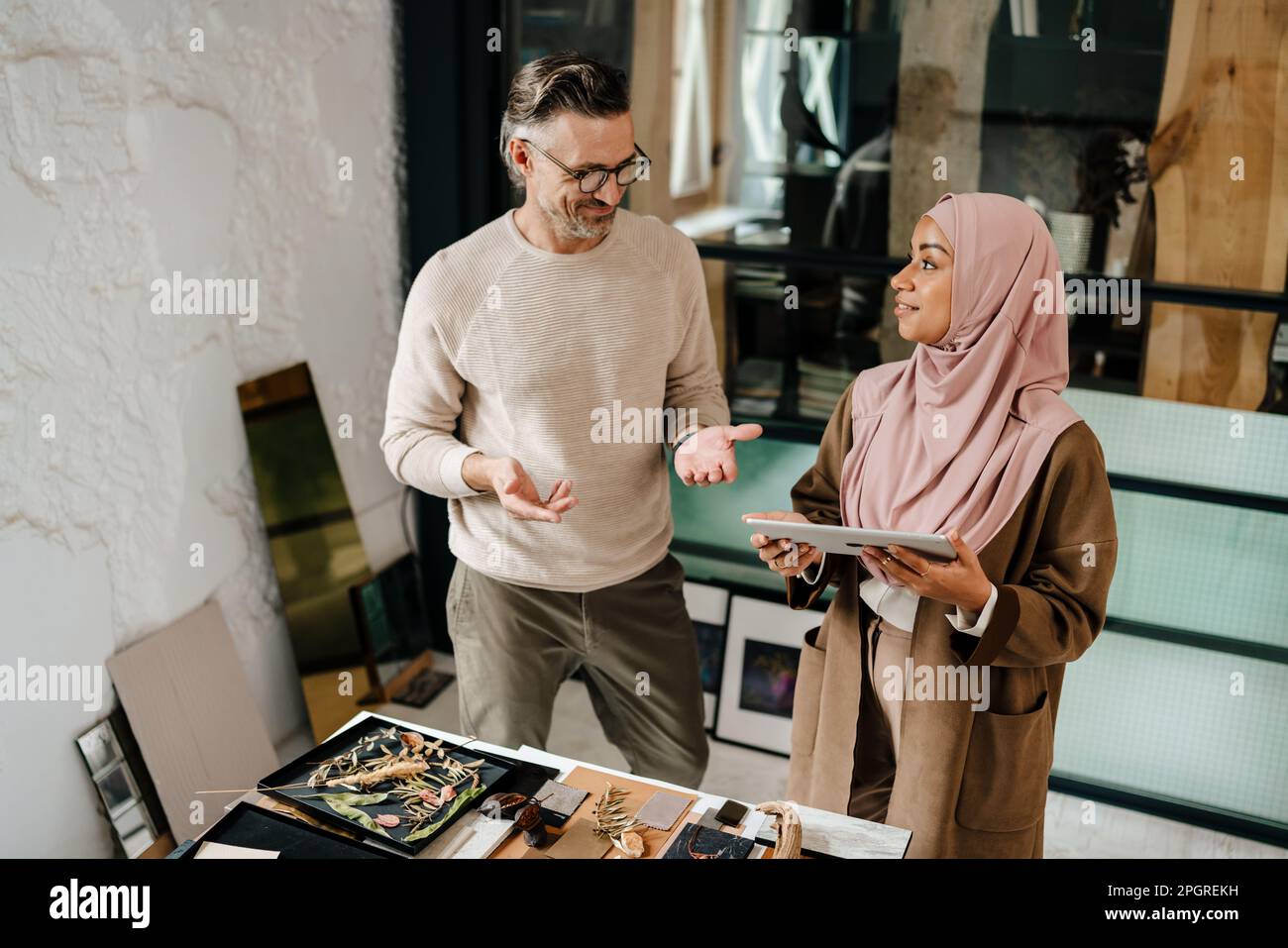 Two multiracial colleagues designers using tablet computer while working together in workshop Stock Photo