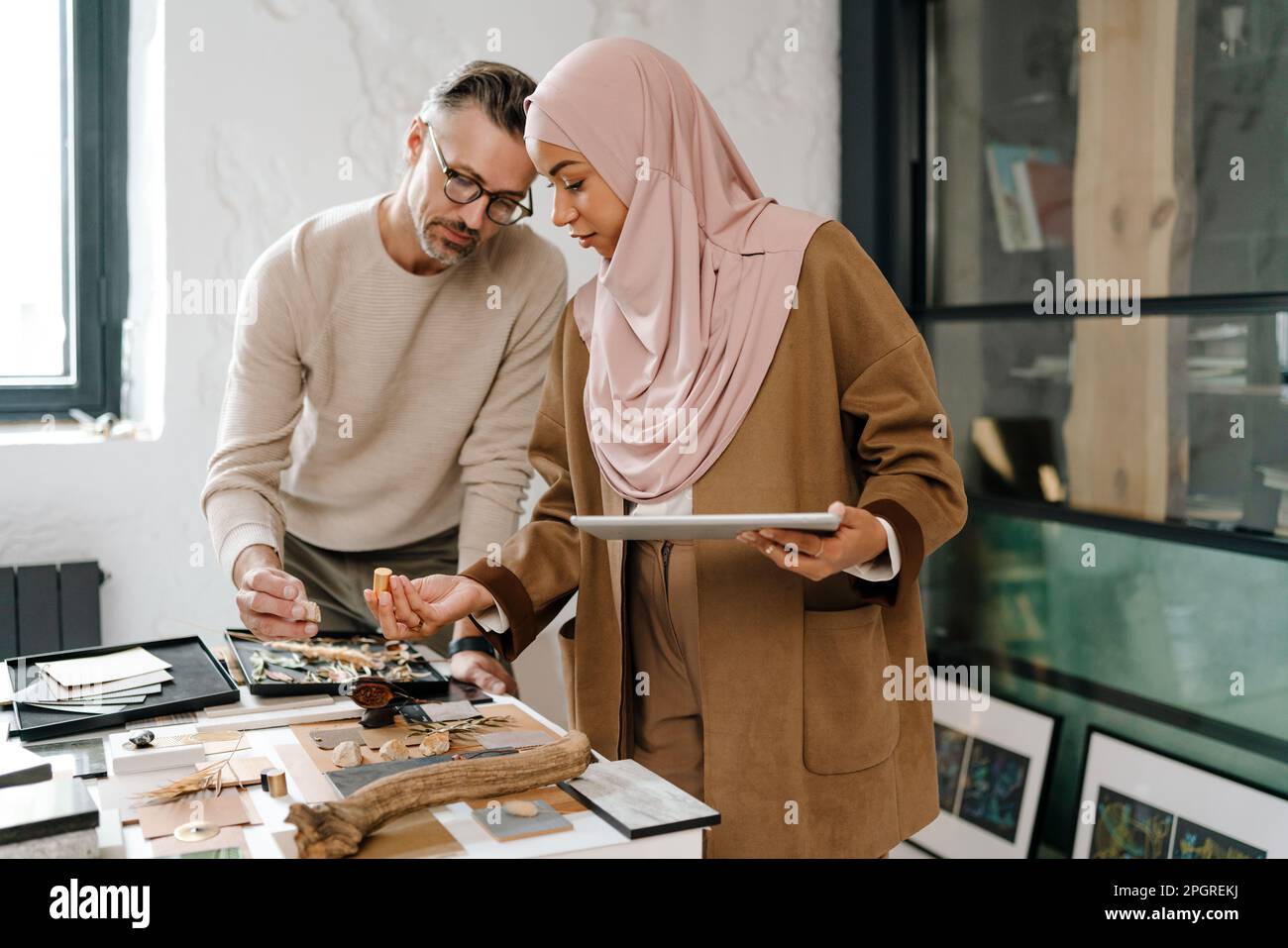 Two multiracial colleagues designers using tablet while working together in modern office Stock Photo