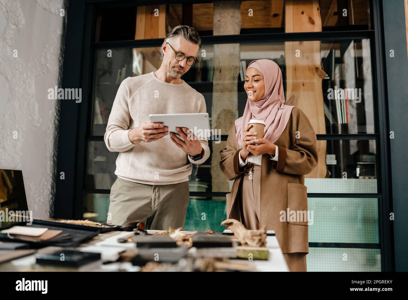 Two multiracial colleagues designers using tablet computer while working together in workshop Stock Photo