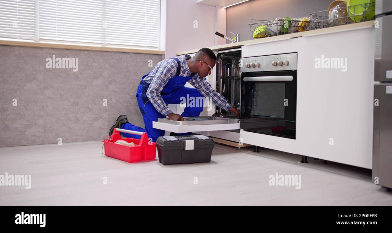 African American Repairman Fixing Dishwasher Appliance Machine Stock