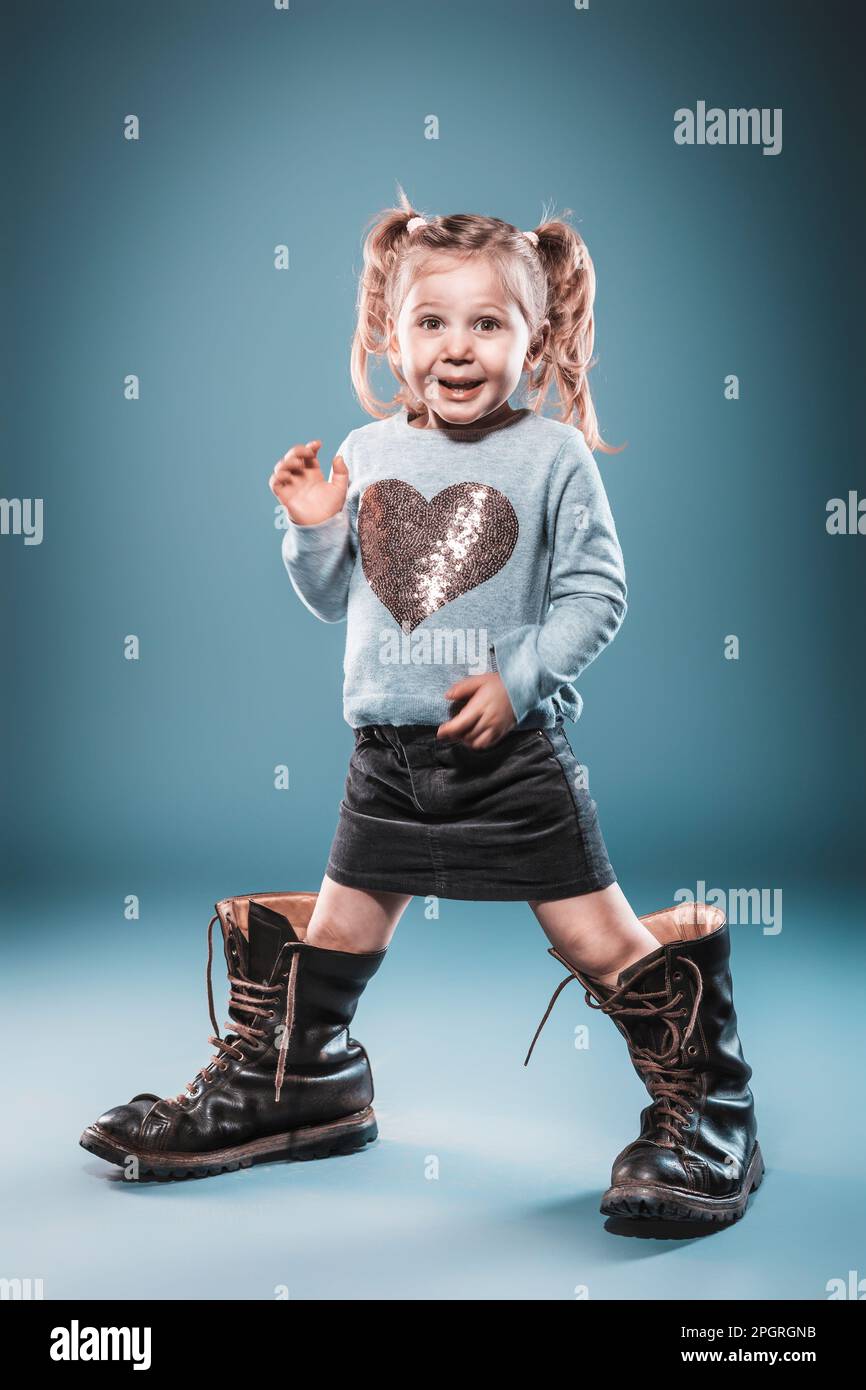 blonde girl plays with big boots. studio shot Stock Photo