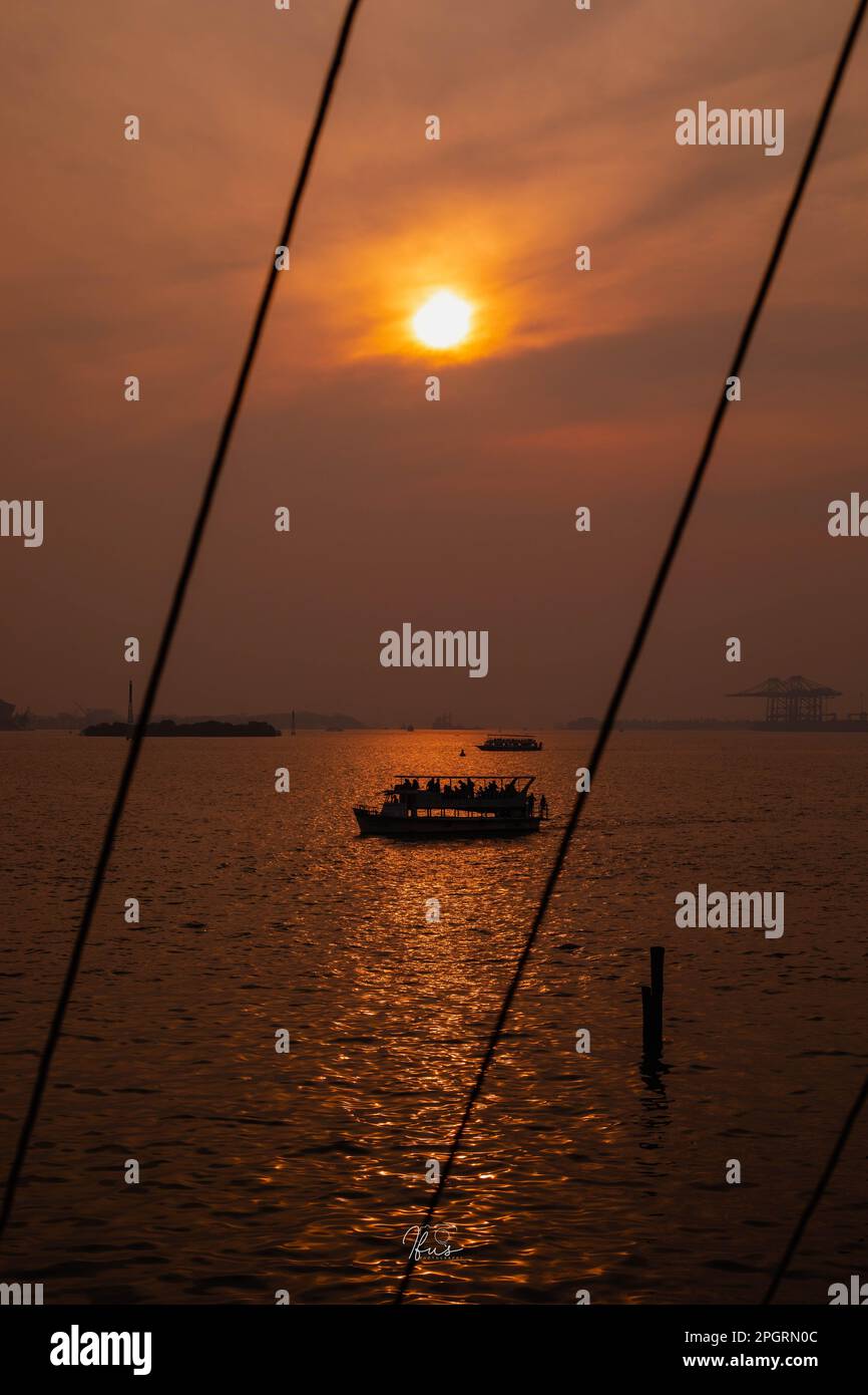 The view of the sea with a silhouette of a boat at sunset Stock Photo ...