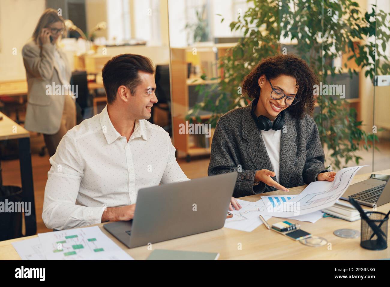 Two colleagues working together with documents while sitting on office desk. Teamwork concept Stock Photo