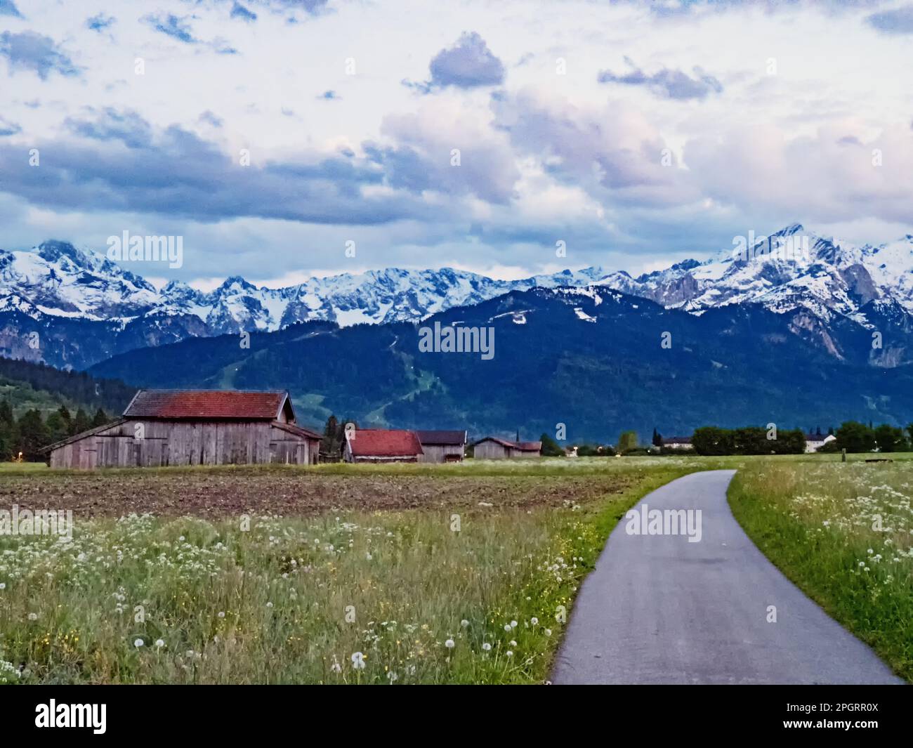 Road in Werdenfelser Land near village Farchant against the backdrop of Wetterstein Mountains, Bavaria, Germany Stock Photo